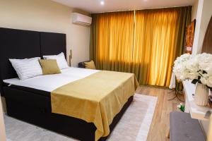 a bedroom with a large bed with a yellow curtain at Tirol Home -Green Apartment in Veliko Tŭrnovo