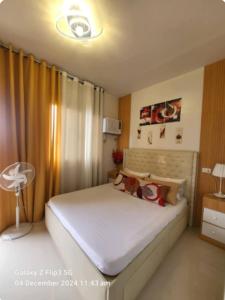 a bedroom with a large white bed with yellow curtains at Jml'spod Royal in Lapu Lapu City