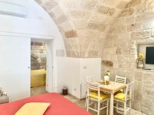 a dining room with a table and chairs and a stone wall at Antica Pietra in Polignano a Mare