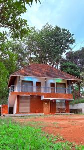 ein rotes und weißes Haus mit einem Balkon in der Unterkunft Athirappilly Heritage Villa - 2BHK -River Side in Athirappilly