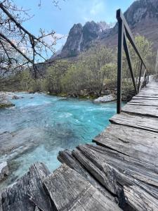 a wooden bridge over a river with mountains in the background at Bujtina Aroma E Malit in Valbonë