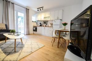 a kitchen and living room with a table and a tv at Apartman Platani in Trebinje