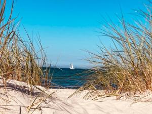 a sail boat in the ocean with a beach at Die Kleine Ferienwohnung in Prerow +8 photos