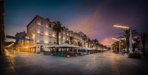 a city street with a building and palm trees at night at Luxury Rooms & Apartment - Main promenade, Sea & City View in Diocletian Palace Split in Split