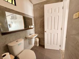 un bagno con un water, un lavandino e uno specchio di Villa Milagros Dive Inn Anilao a Bagalañgit