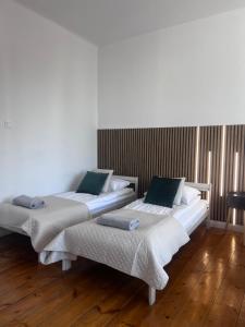 two beds in a room with wooden floors at Na Deskach Apartments in Żyrardów +8 photos