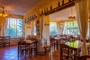 a dining room with tables and chairs and windows at Fattoria Terra e Libertà in Contrada Maeggio