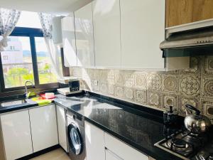 a kitchen with white cabinets and a washer and sink at Colina Smir par Immo Marina Vacances de Rêve B2-6 in Sania Torres