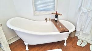 Una bañera blanca en un baño con ventana. en Karoo Vreugde, en Merweville