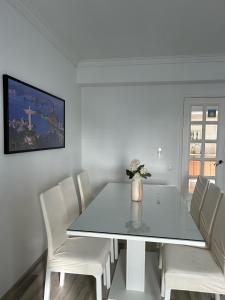une salle à manger blanche avec une table en verre et des chaises blanches dans l'établissement Mima House Al, à Aveiro