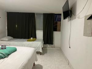 a hotel room with two beds and a television at Hotel y restaurante juanchito in Pitalito