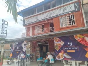 a man sitting at a table in front of a restaurant at Hotel y restaurante juanchito in Pitalito