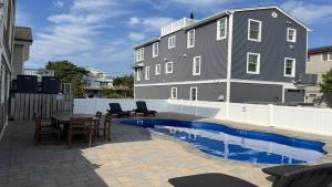 un patio con tavolo, sedie e una casa di Pet Friendly, Bayside Surf City, Private Yard, Pool, Elevator Roof Top Deck Beach Badges a Surf City