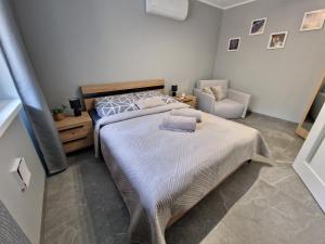 a bedroom with a large bed and a chair at Mario Leśny Klif 21 in Debina
