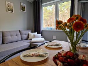 a living room with a couch and a table with flowers at Mario Leśny Klif 21 in Debina