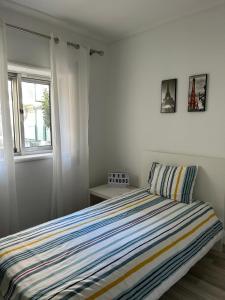 - une chambre avec un lit doté d'une couette à rayures et d'une fenêtre dans l'établissement Mima House Al, à Aveiro