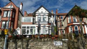 una grande casa con una recinzione di fronte di Whitehall Guest House a Colwyn Bay