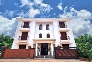 a white house with a fence in front of it at Casa Pallazzo Luxury Villa - 10BHK Private Pool in Baga