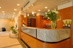 eine Lobby mit einem Tresen, auf dem eine Vase mit Blumen steht in der Unterkunft Hotel Le Roi in Varraze