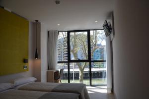 sypialnia z dwoma łóżkami i dużym oknem w obiekcie Hotel Bilbao Plaza w mieście Bilbao