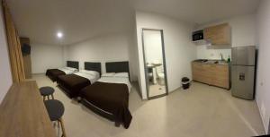 a bedroom with two beds and a kitchen with a refrigerator at apartamentos villa 1blanca in Popayan