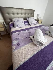 - un lit violet avec des serviettes et des oreillers dans l'établissement Adosado con vistas al Mar Menor y parking, à Santiago de la Ribera