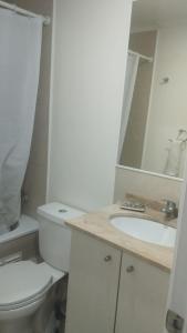 a white bathroom with a toilet and a sink at Cumbres de reñaca 922 in Viña del Mar