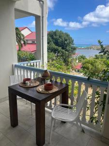 a table and chairs on a balcony with a view of the ocean at Joli Studio vue Mer avec Piscine in Cul de Sac