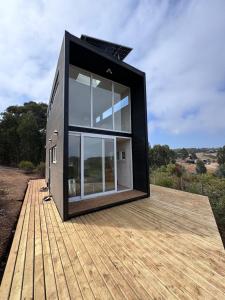 ein schwarzes Haus auf einem Holzdeck in der Unterkunft Koru Ecolodge in Cáhuil