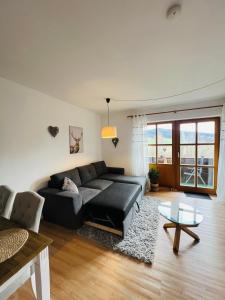 a living room with a black couch and a glass table at Idyllische Ferienwohnung am Geiersberg in Hauzenberg