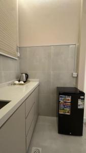 a small kitchen with a counter and a refrigerator at Luxury Smart Entry Studio in Buraydah