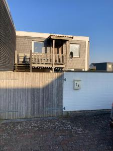 a house with a deck on top of a fence at Strandhuus Westerbergen - direkt am Meer bei Lemkenhafen in Fehmarn