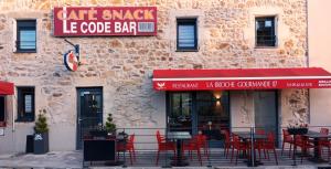 a cafe with red tables and chairs in front of a building at Gite d'étape le code bar in Saint-Julien-Labrousse