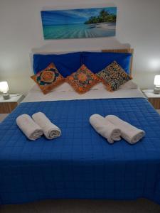 a blue bed with two pillows on it with blue sheets at Appartamento L'Orchidea in Forio d'Ischia