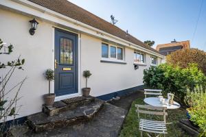 a white house with a blue door and a table at Spacious one bed apartment in a quiet leafy close. in Barnstaple