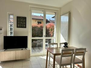 een eetkamer met een televisie en een tafel en stoelen bij Bellagio Wave Apartment in Bellagio