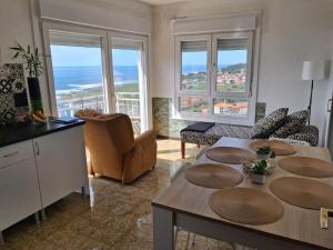 a living room with a table and chairs and windows at Alojamiento Chavella in Oia