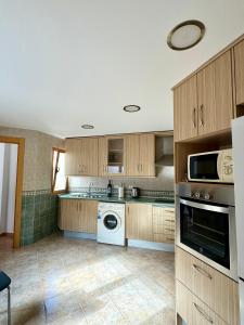 a kitchen with wooden cabinets and a washer and dryer at Ático Luz del Valle in Dúrcal