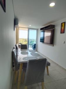 a dining room with a table with chairs and a television at Apto Vista Mar 2 cuadras Playa, Jaccuzi BBQ Wifi Parqueadero y Ascensor 7 Piso in Santa Marta