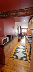 a kitchen with wooden cabinets and a microwave on the counter at La Frisanfave, Maison de village, centre 65M2 in Abriès