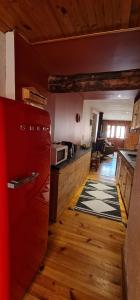 a kitchen with wooden floors and a red refrigerator at La Frisanfave, Maison de village, centre 65M2 in Abriès