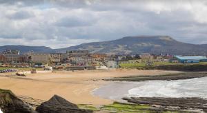 a beach with a town and a mountain in the background at Beach Apartment Bundoran in Bundoran