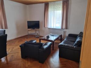 a living room with black leather furniture and a television at Ferienwohnung 2 mit 3 Schlafzimmer und Garten in Crailsheim