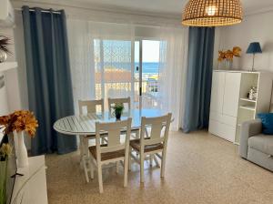 a dining room with a table and chairs and the ocean at Apartamento El Sol in Piles +17 photos