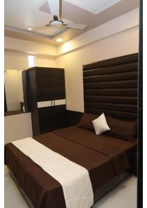 艾哈迈达巴德Hotel rk palace的一间卧室配有一张大床和棕色床头板