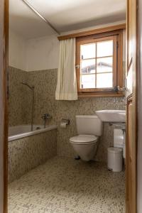 a bathroom with a toilet and a sink and a tub at Haus 3 - 5 Zimmer Haus mit Garten in ruhiger Wohngegend in Laax-Murschetg