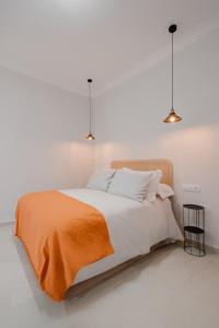 a bedroom with a bed with an orange blanket on it at Apartamento Don Marcos A in Badajoz