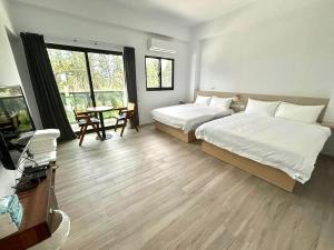 a bedroom with two beds and a table and a window at oceya in Magong