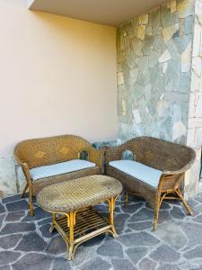 three wicker chairs and a table in front of a stone wall at Civico 7 in Clusane sul Lago