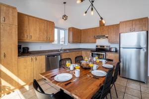 a kitchen with a wooden table and a stainless steel refrigerator at Bleuzen appartement du haut in Petite-Rivière-Saint-François